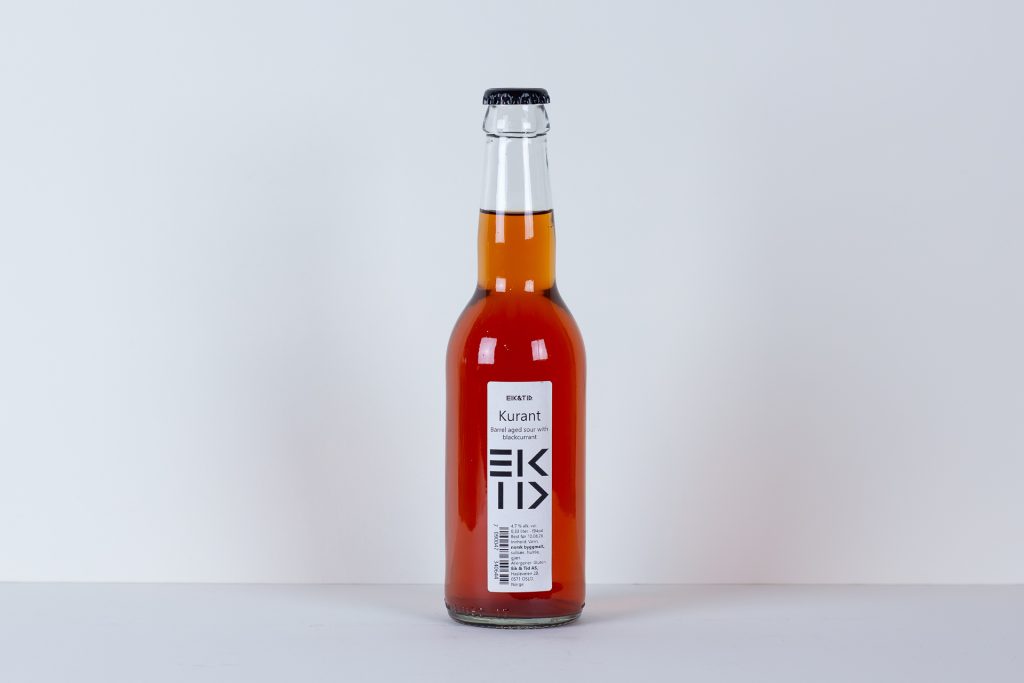 Center front glass bottle with amber liquid and a white Kurant label against a plain light background