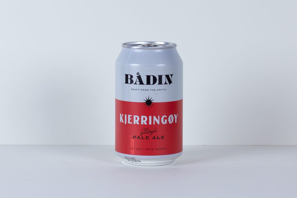 Tall beer can centered on a white surface white top label and red bottom with BÅDIN and KJERRINGØY on the label