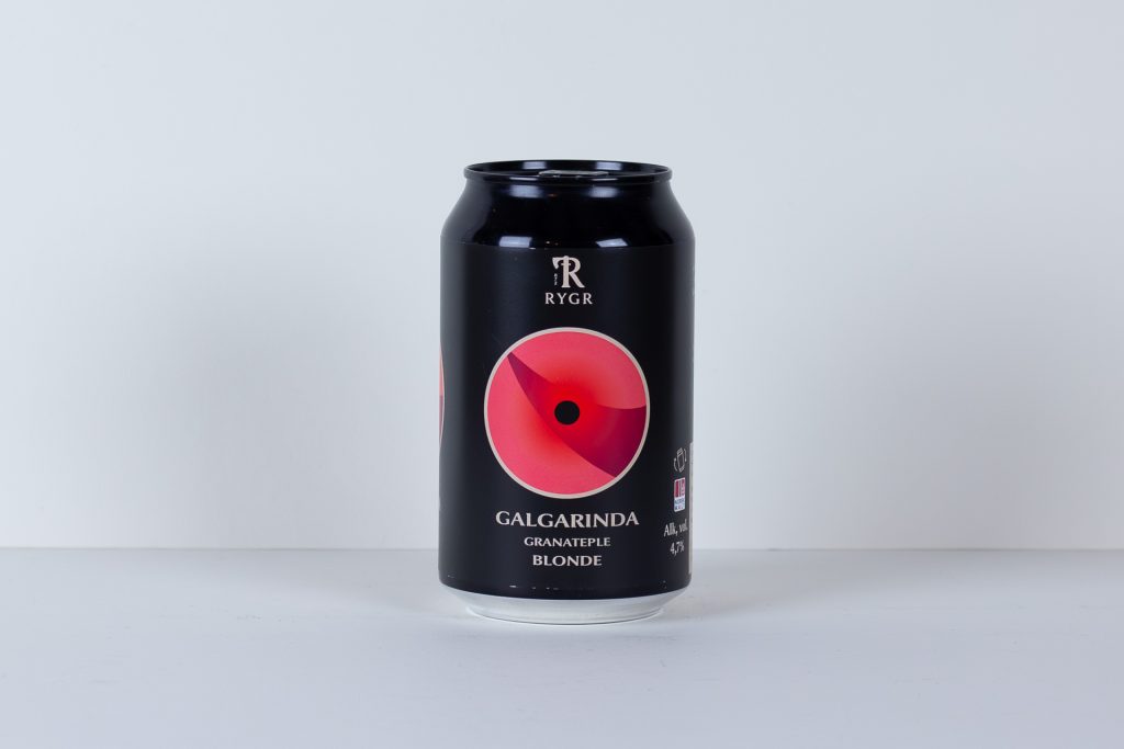 Black beverage can with a large pink circular emblem and white text on a light background standing on a white surface