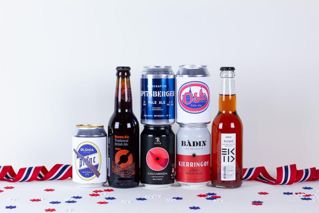 Row of craft beer bottles and cans on a white surface with red, white, and blue confetti and streamers in the foreground.